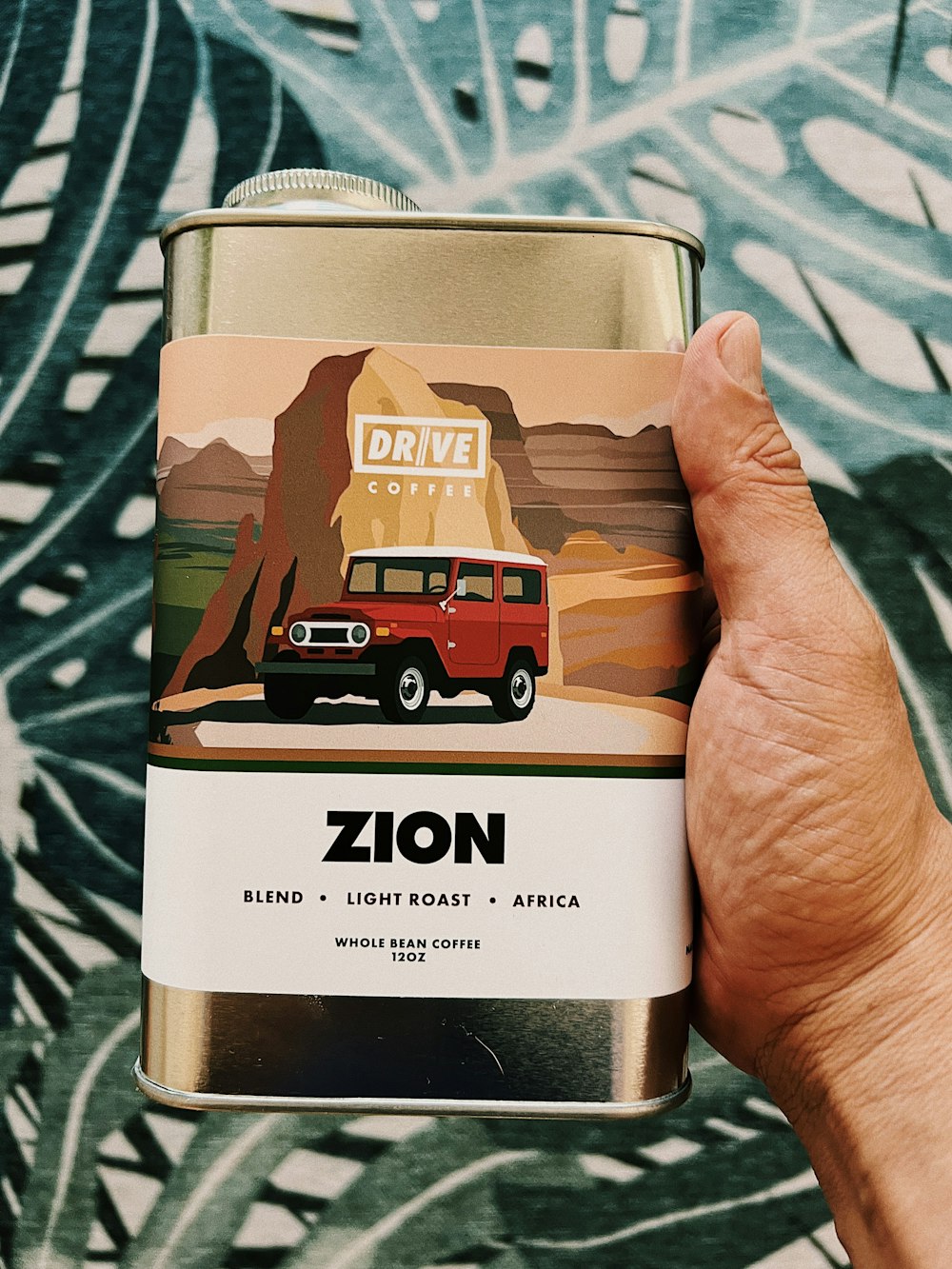 a hand holding a can of zon coffee