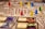 A close-up of a detailed board game in progress with various colored game pieces, such as red, yellow, blue, and green, placed on a textured map. There are also several cards with text and images on them, adding to the intricate and immersive nature of the game.