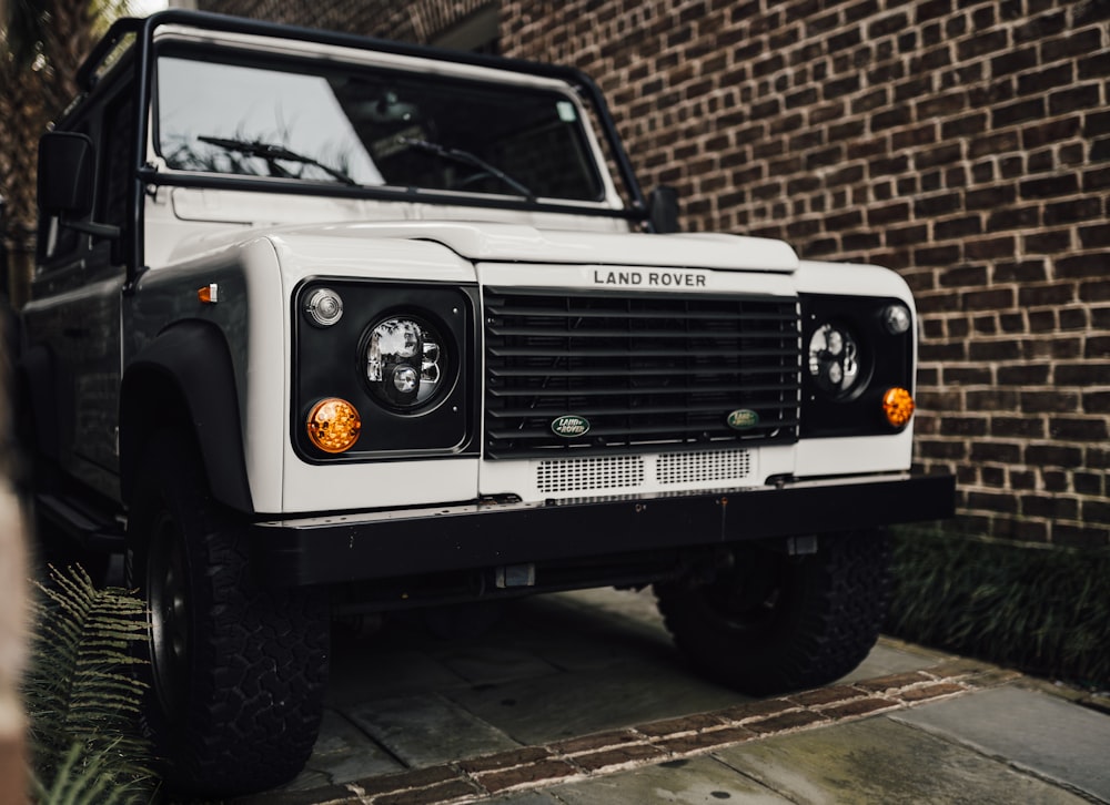a white land rover parked in front of a brick building