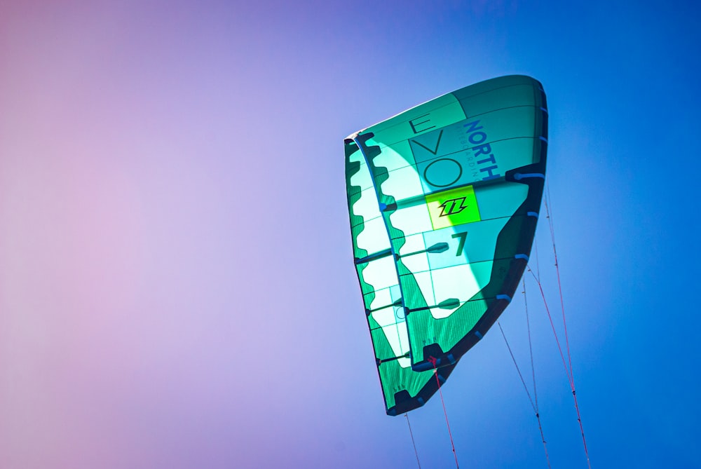 a green and white kite flying in the sky