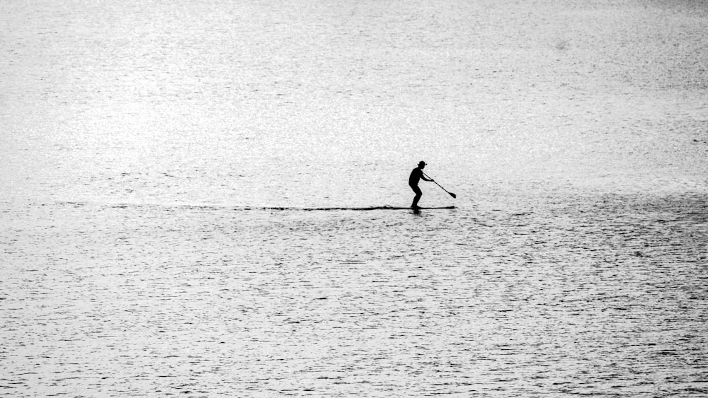 eine Person, die auf einem Paddelbrett auf einem Gewässer fährt
