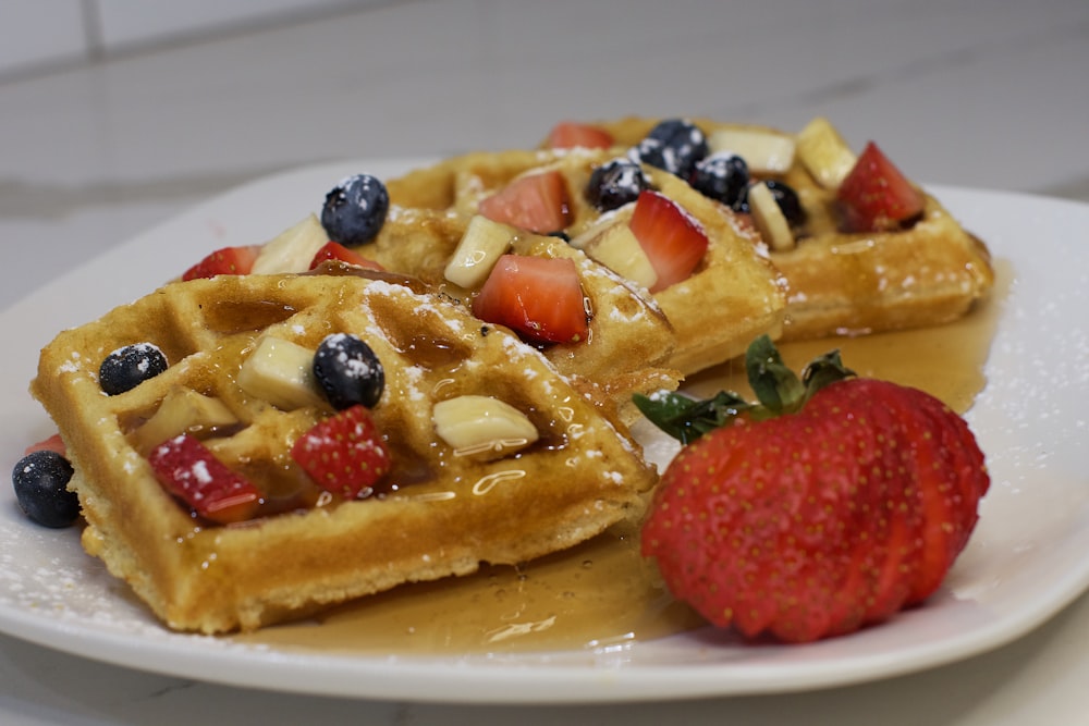 a plate of waffles with fruit on top