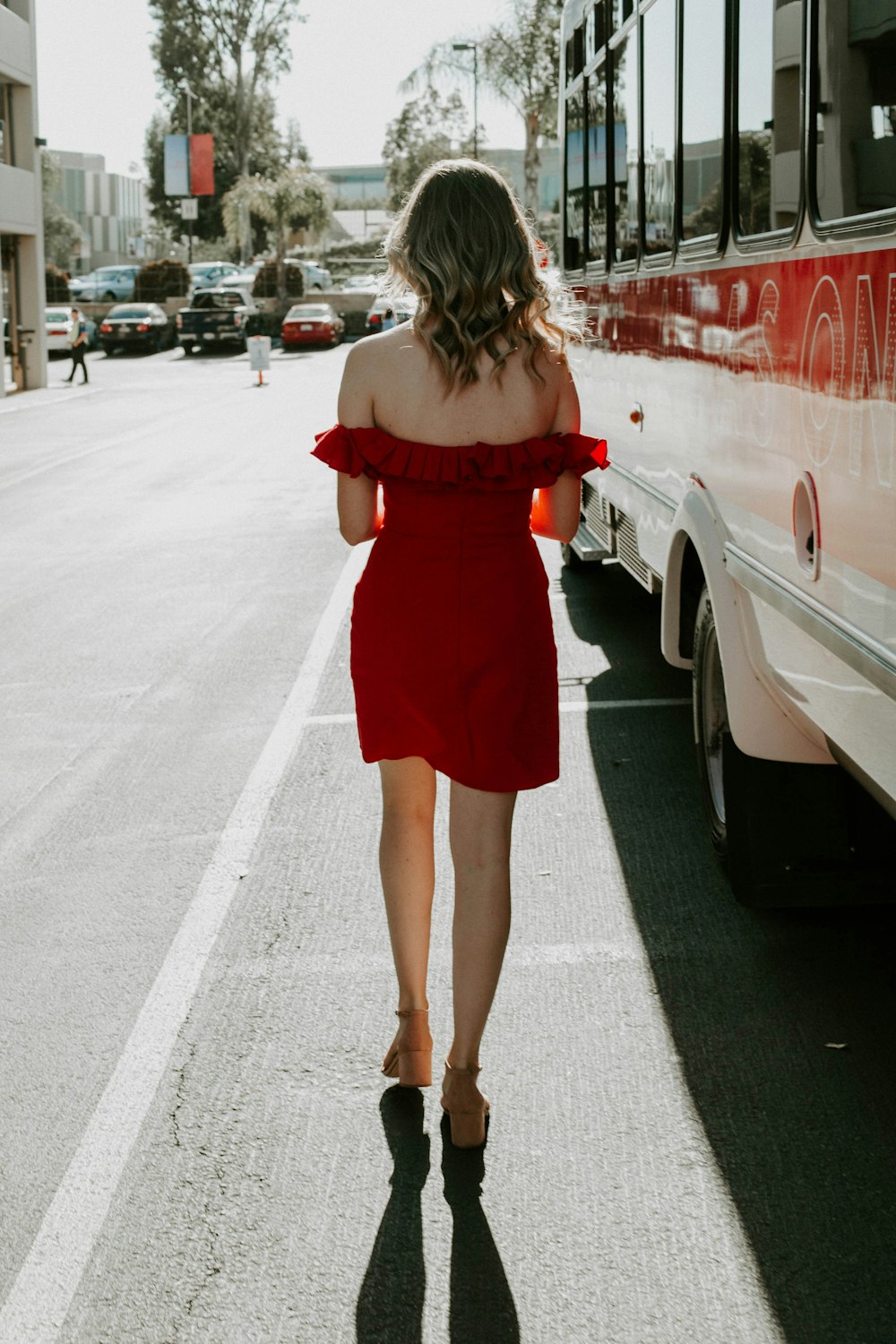 a woman in a red dress is walking down the street