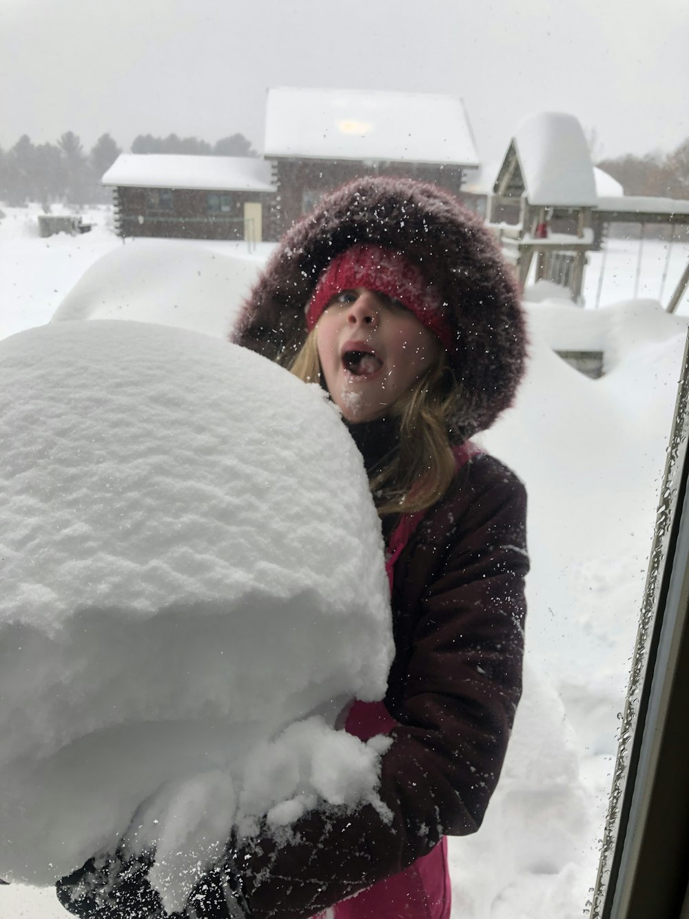 a little girl standing in front of a window covered in snow