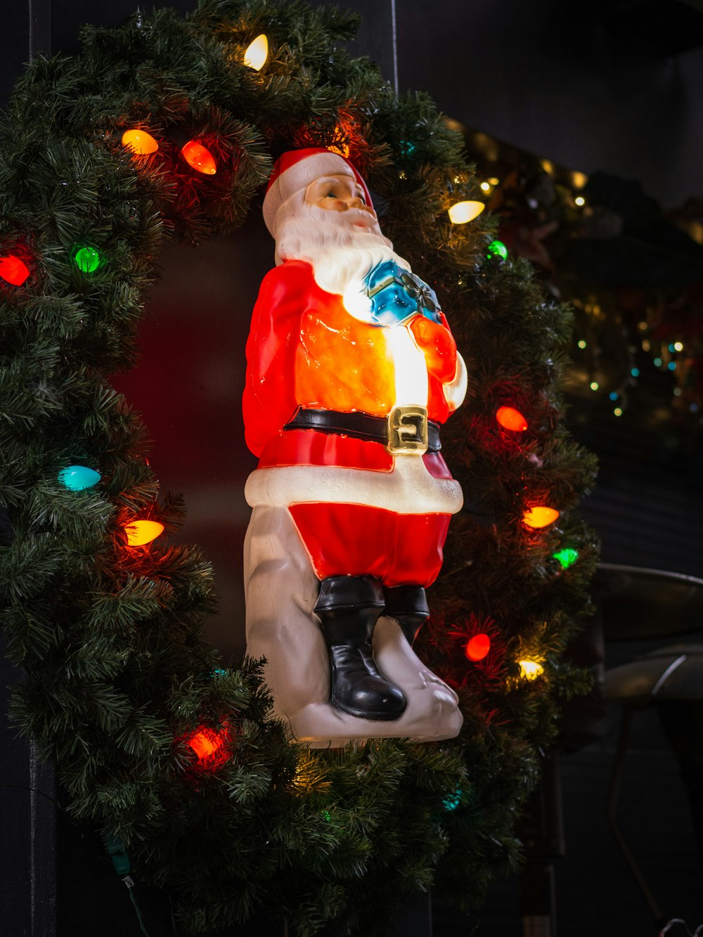 a statue of a santa clause hanging from a christmas wreath