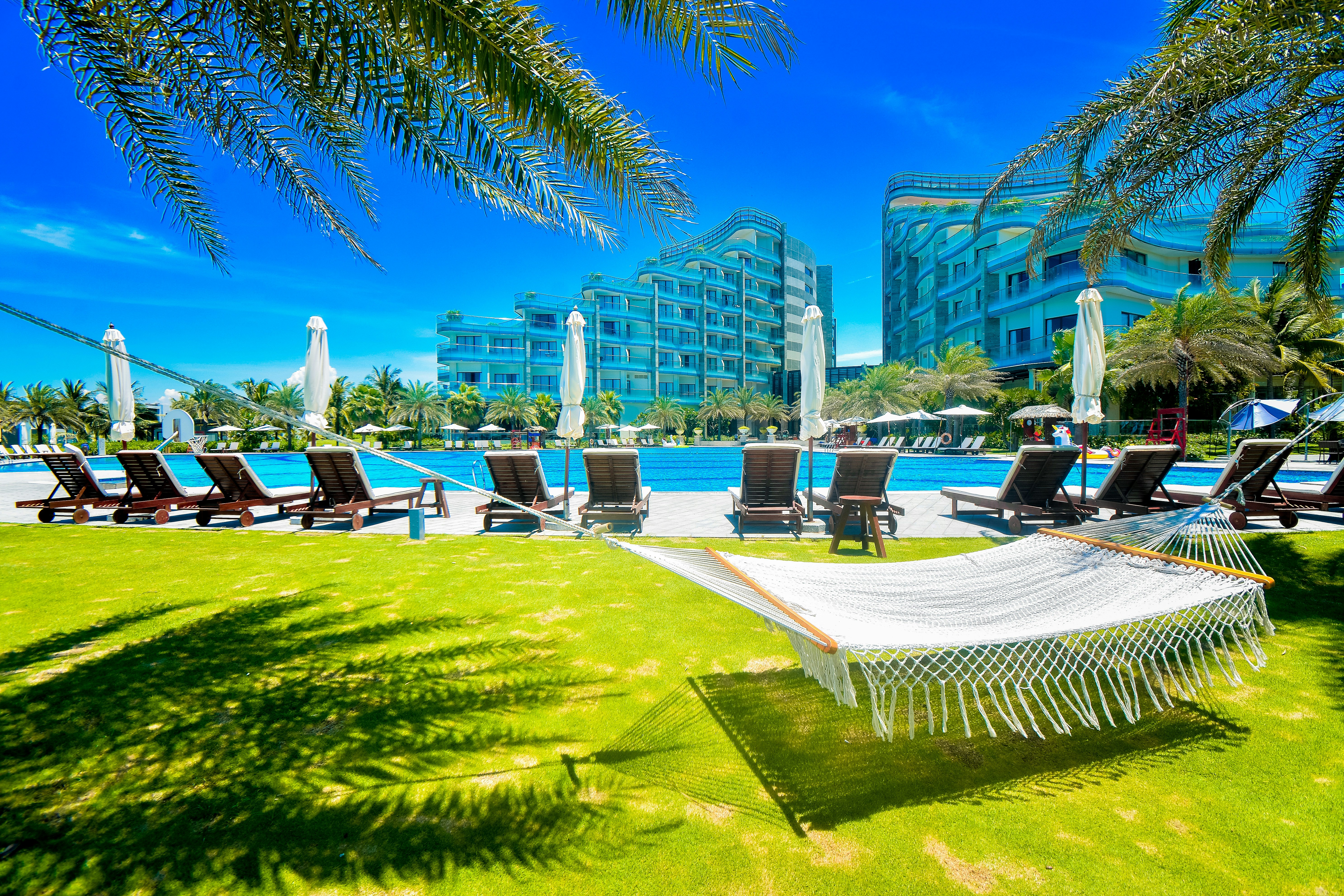 a hammock sitting in the grass next to a swimming pool, Summer Vacation In Vinpearl Nam Hoi An