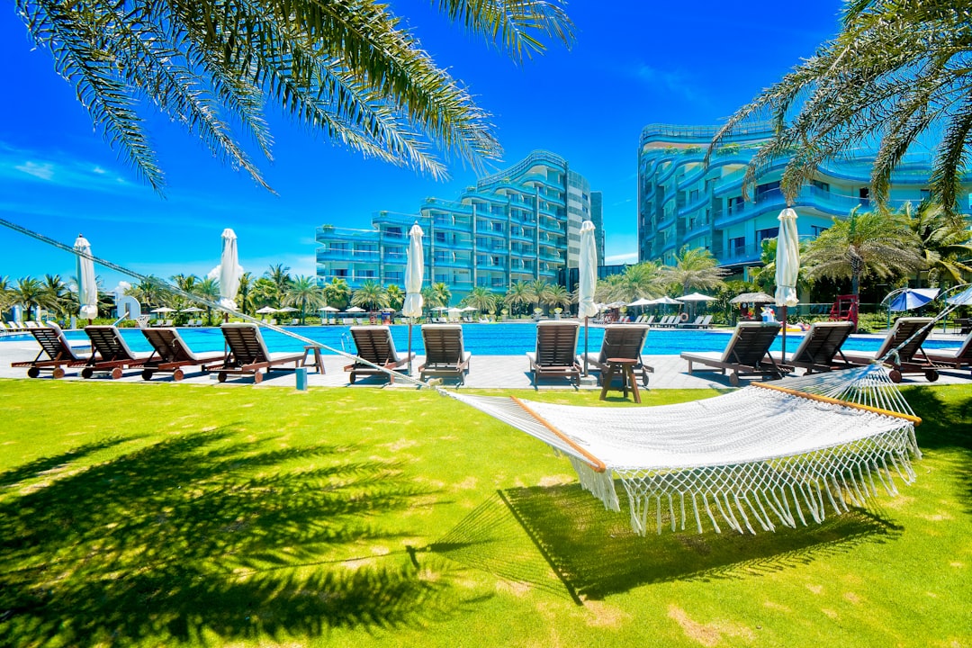 a hammock sitting in the grass next to a swimming pool, Summer Vacation In Vinpearl Nam Hoi An