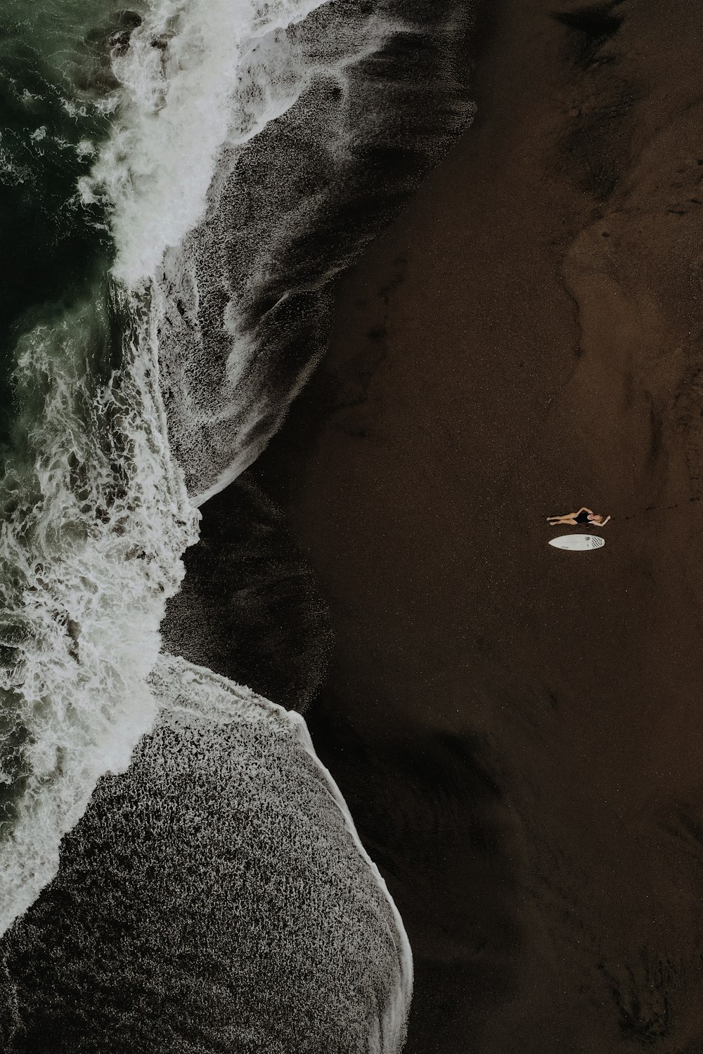 a person laying on top of a surfboard on a beach