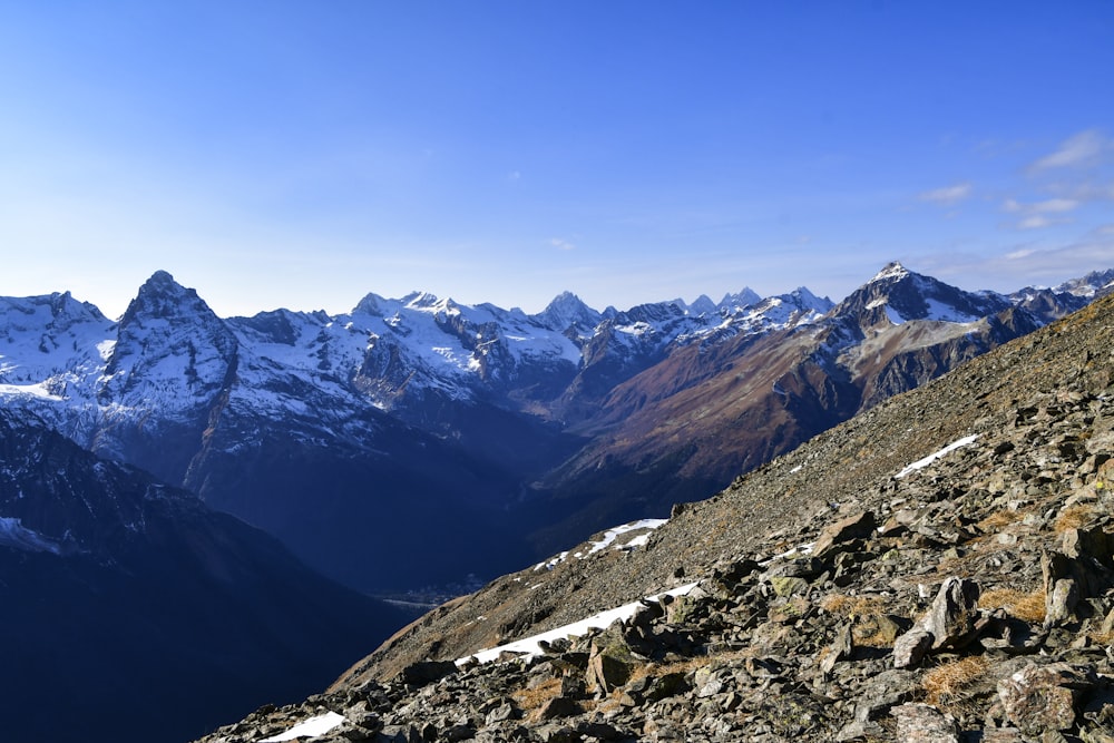 a rocky mountain with snow capped mountains in the background