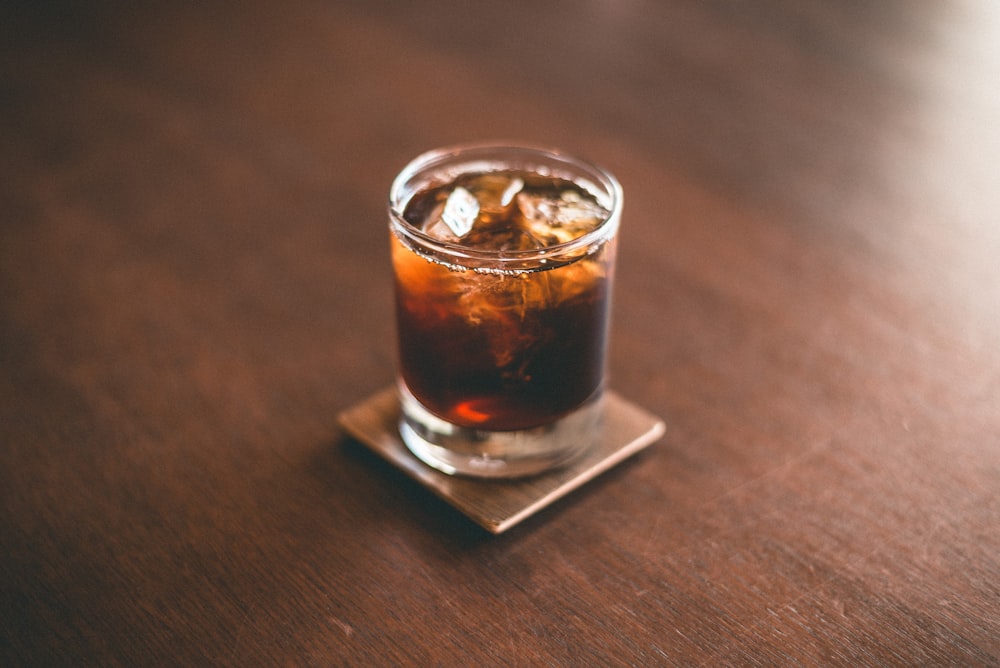 a glass of soda sitting on top of a wooden table