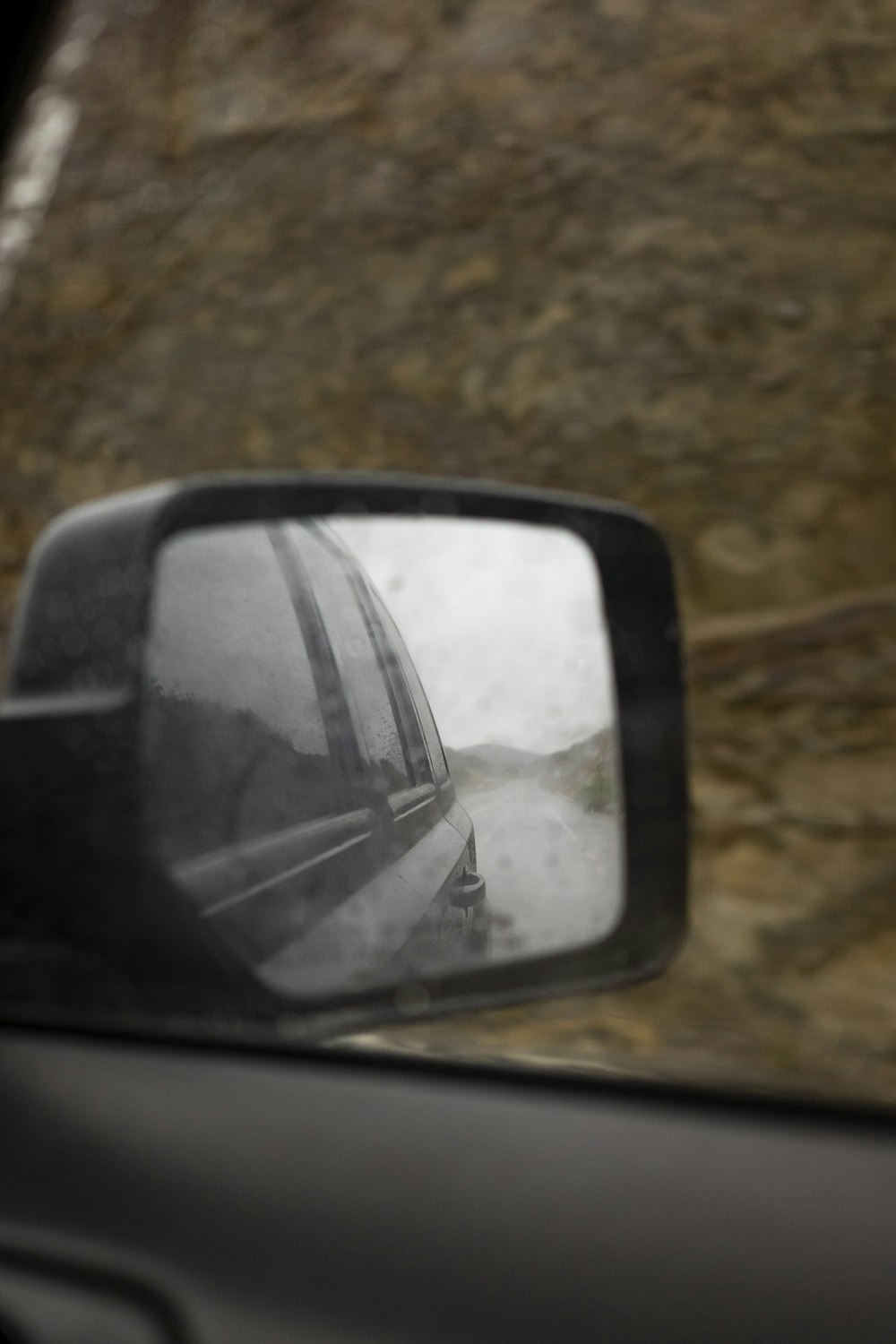 a side view mirror on a car with a mountain in the background