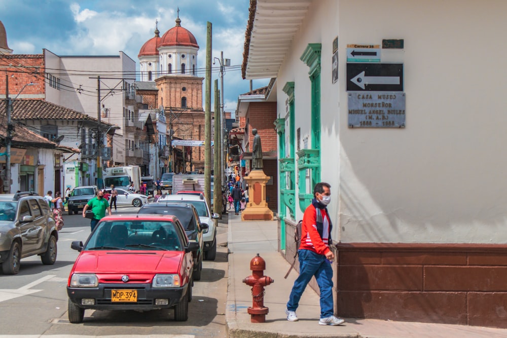 a man standing on the side of a street next to a red fire hydrant