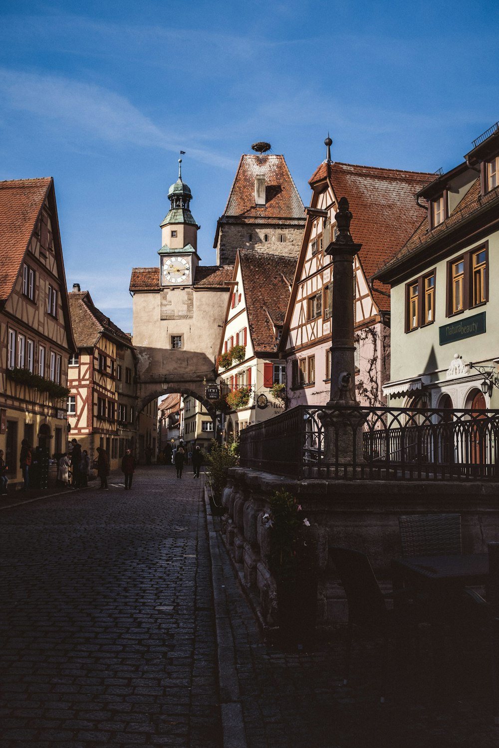 a cobblestone street lined with buildings and a clock tower