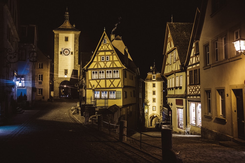 a street at night with a clock tower in the background