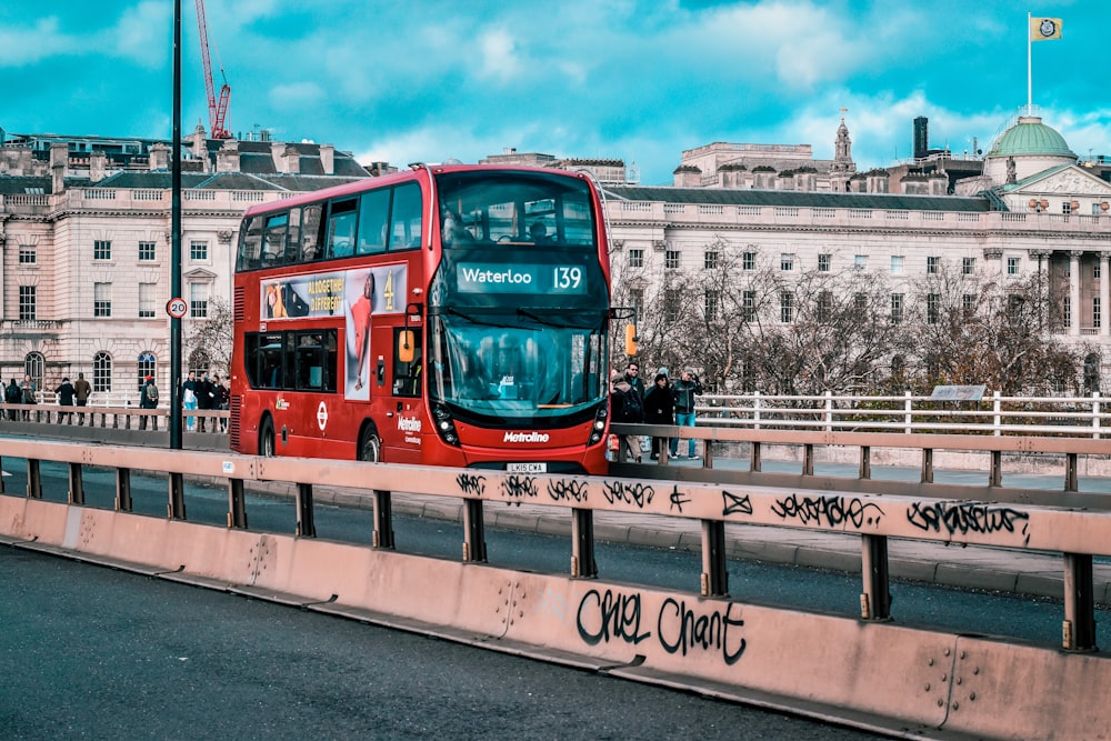 a red double decker bus driving over a bridge