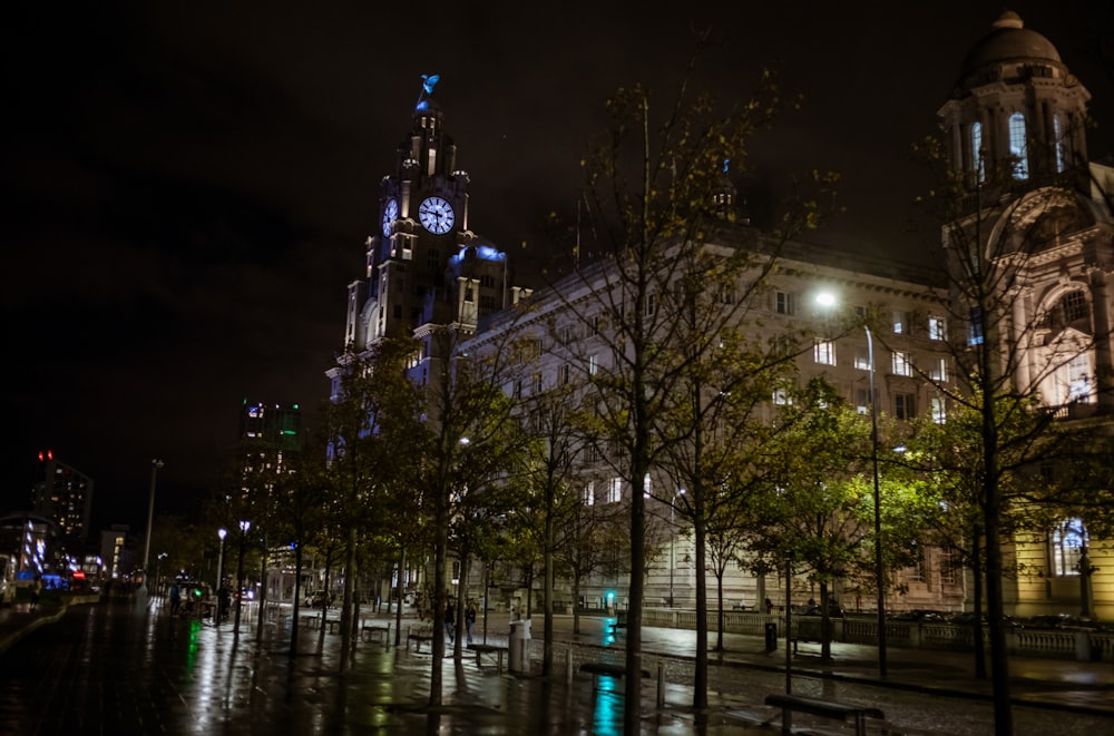 Una strada della città di notte con una torre dell'orologio sullo sfondo