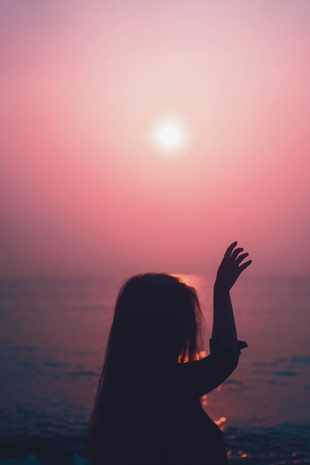 a silhouette of a woman with her hands up in the air