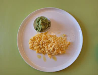 A colorful plate with scrambled eggs, avocado slices, and a sprinkle of pumpkin seeds.