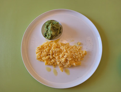 A vibrant plate of creamy scrambled eggs with avocado slices and cherry tomatoes, perfect for a keto breakfast.