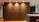 Close-up of a smiling woman admiring a walnut wood wall shelf in a modern living room.