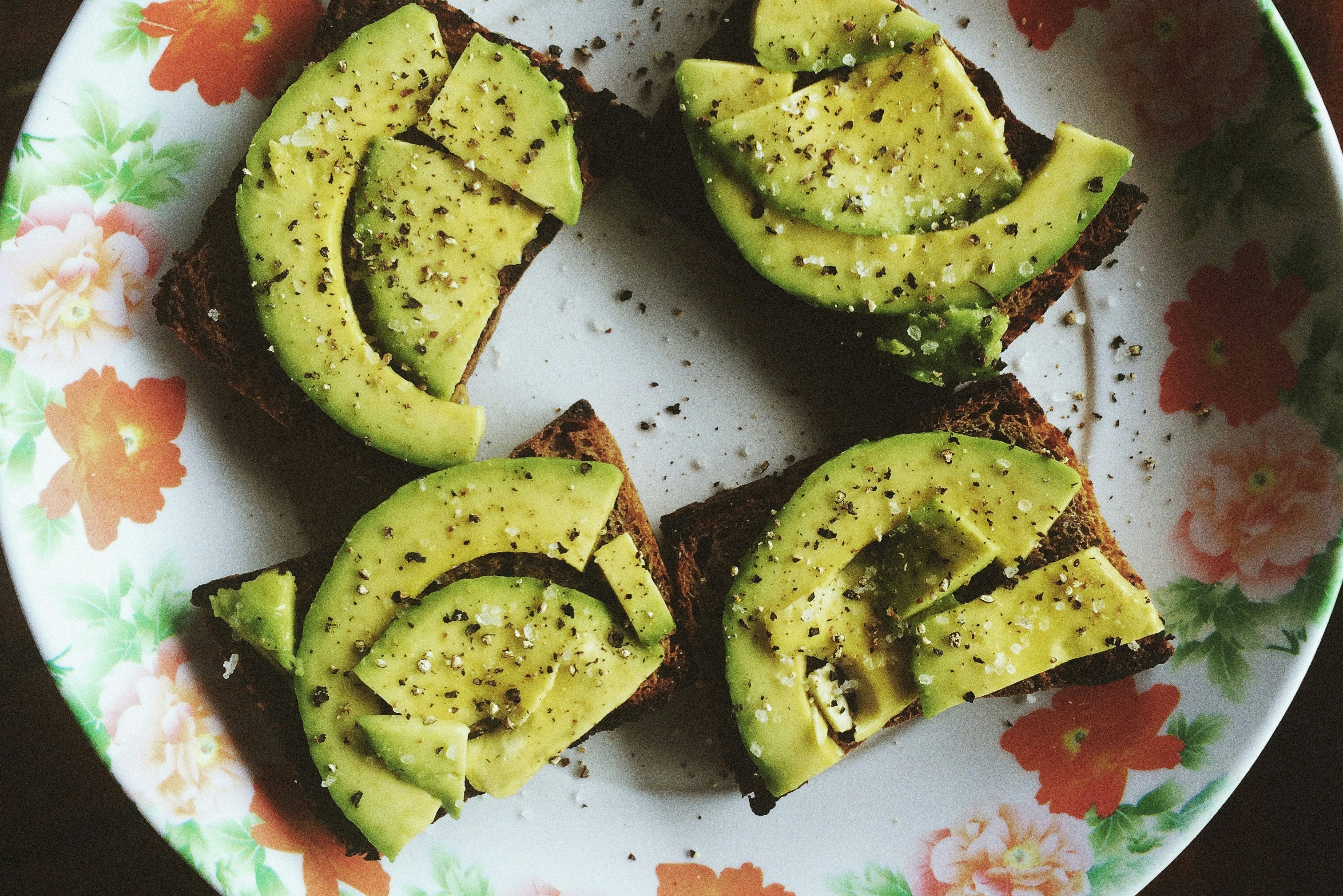 Four avocado toasts on a floral plate