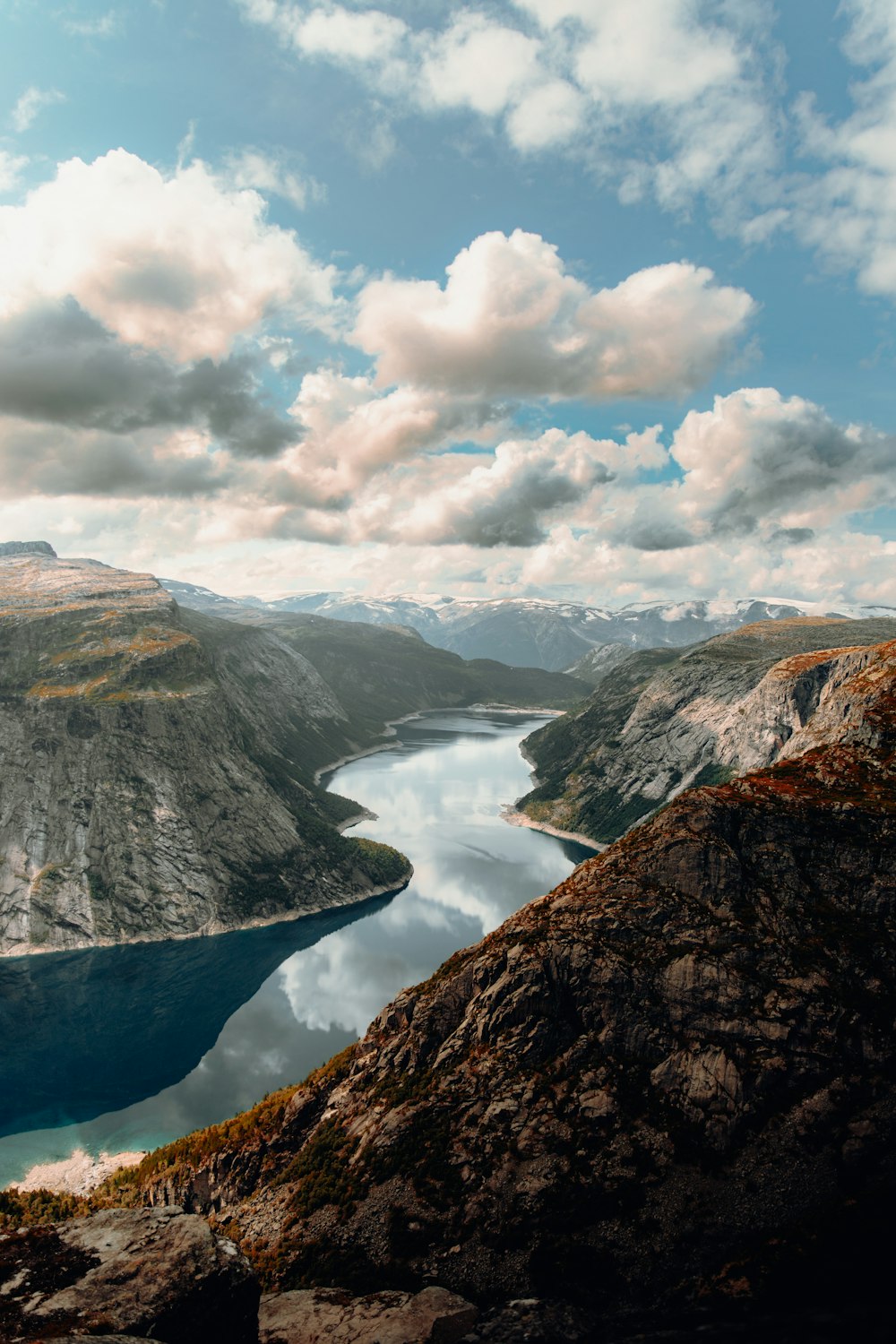 a lake surrounded by mountains under a cloudy sky