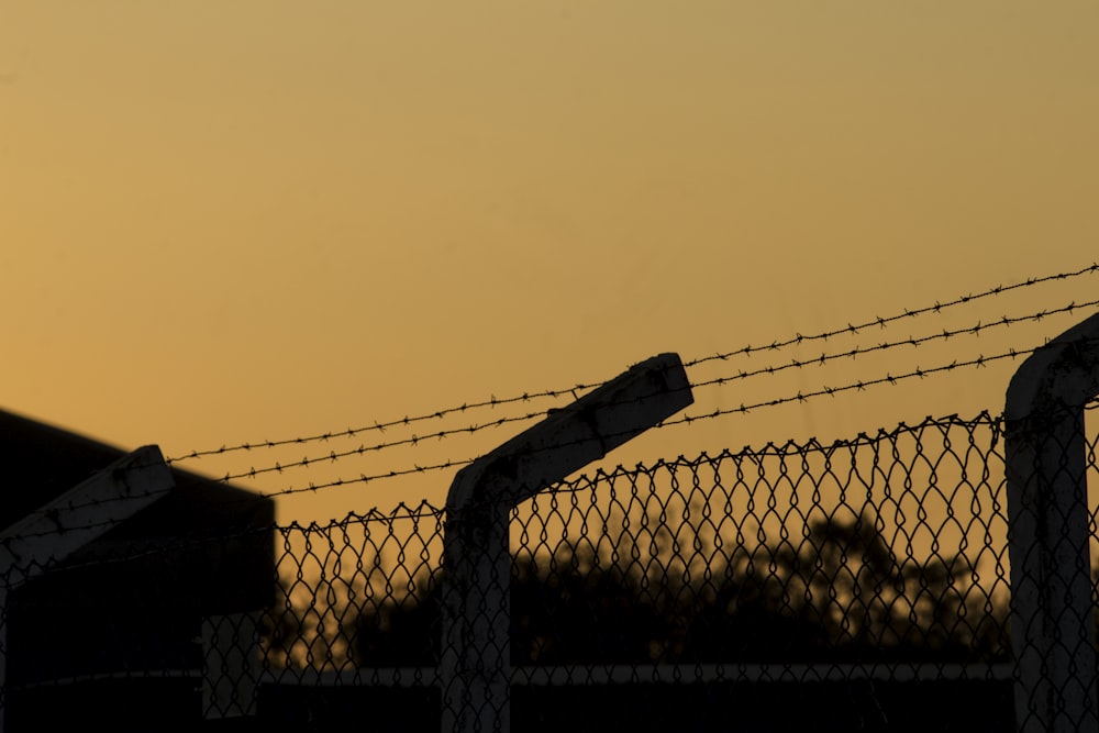 a barbed wire fence with a sunset in the background