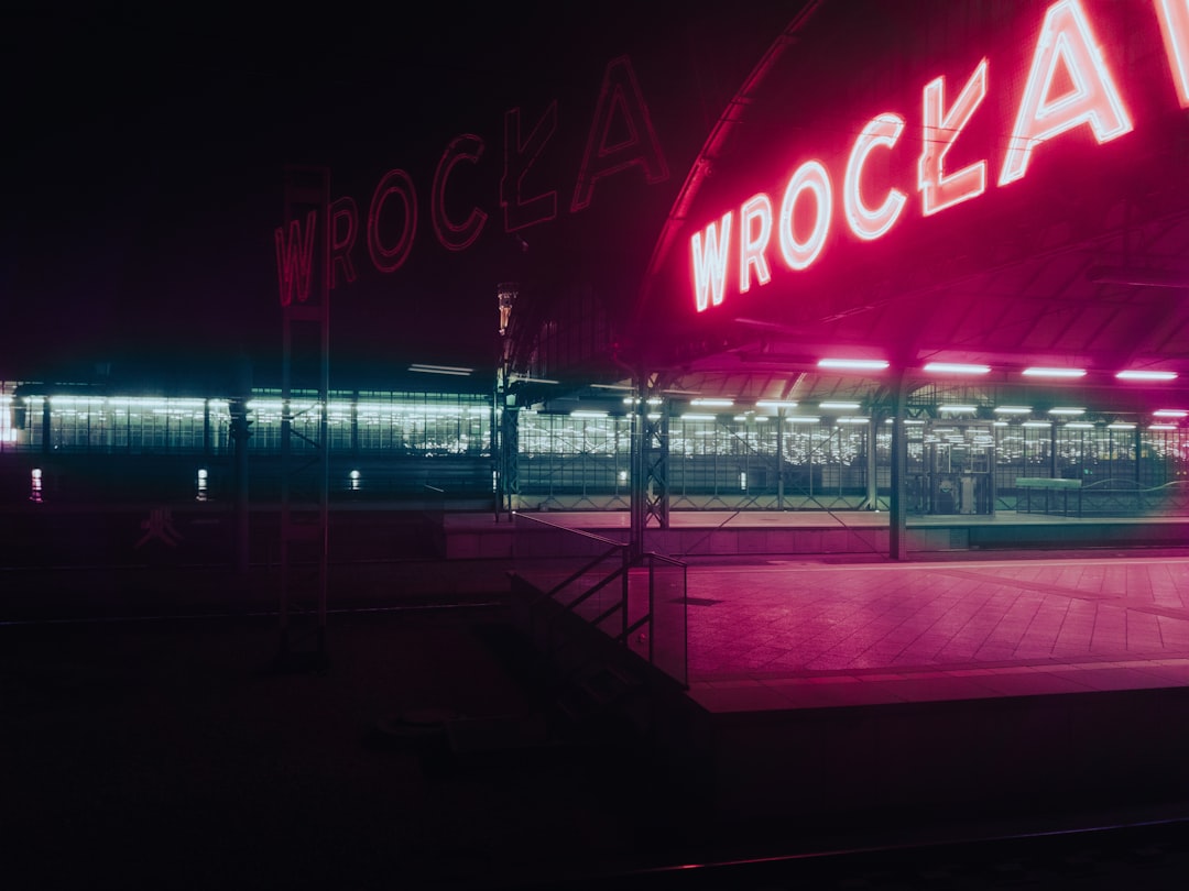 a large neon sign is lit up at night, Wroclaw train station from the Nightjet