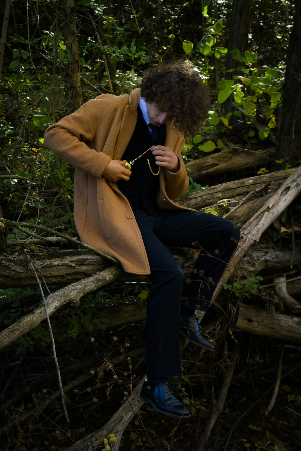 a man sitting on a tree branch in the woods