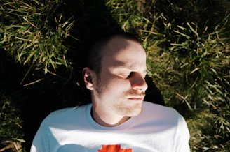 a man laying in the grass with his eyes closed