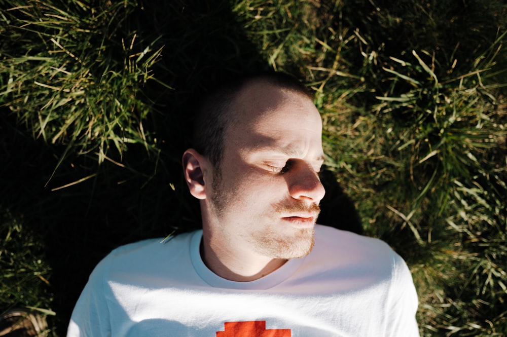 a man laying in the grass with his eyes closed
