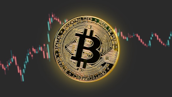 a bitcoin is shown in front of a stock chart
