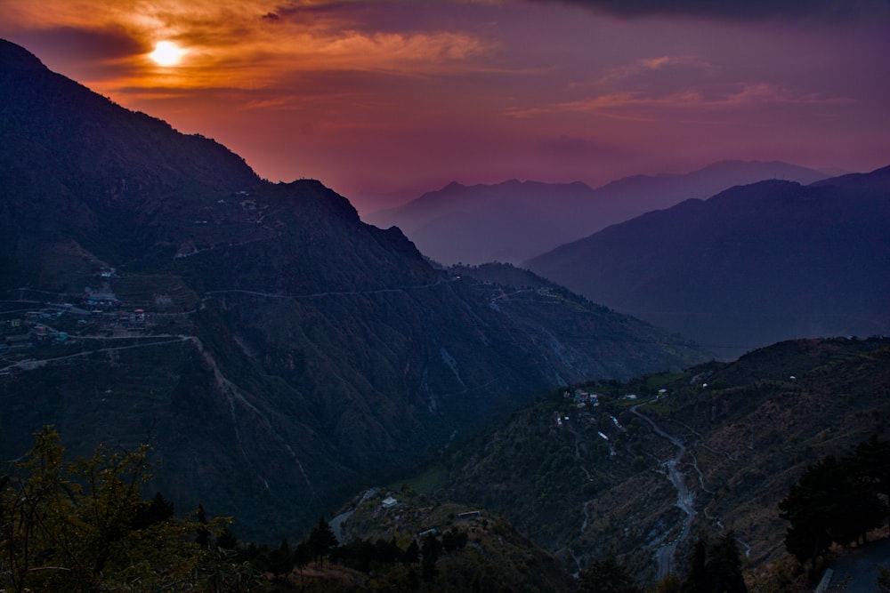 the sun is setting over a mountain range