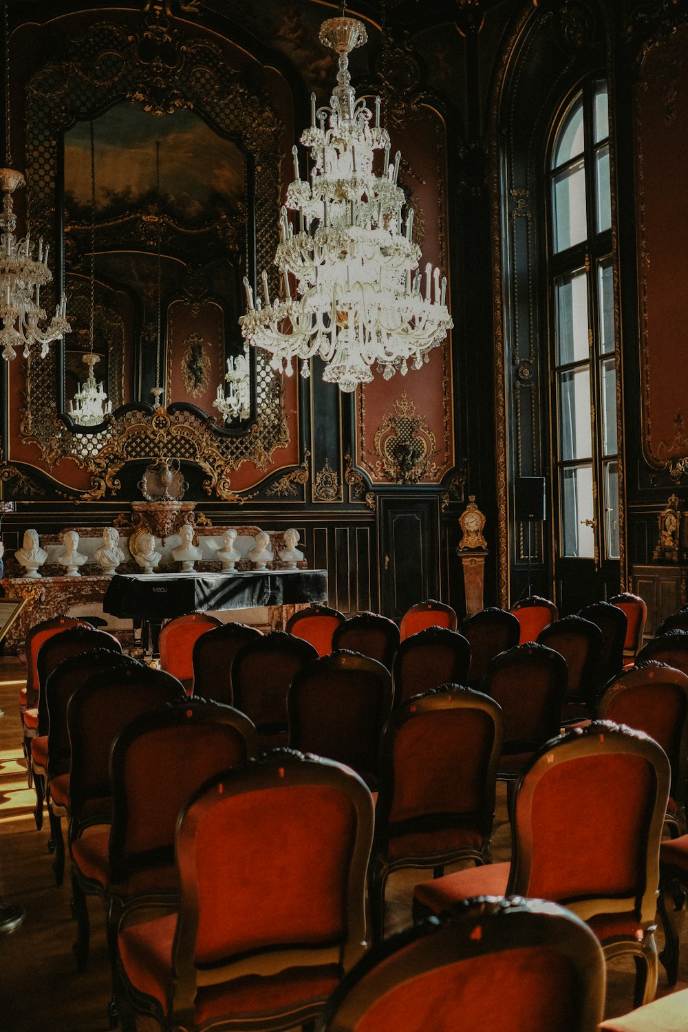 a room filled with lots of red chairs and a chandelier