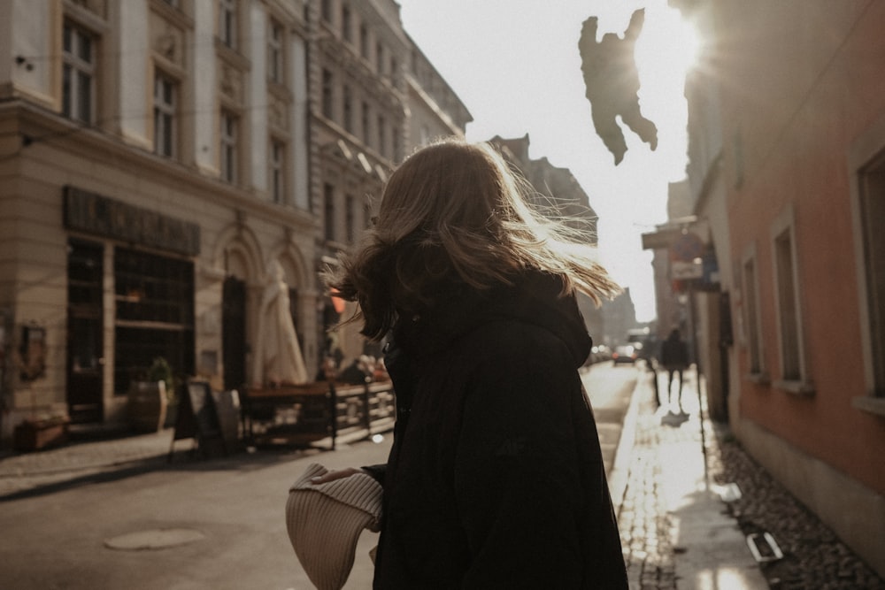 a woman walking down a street next to tall buildings