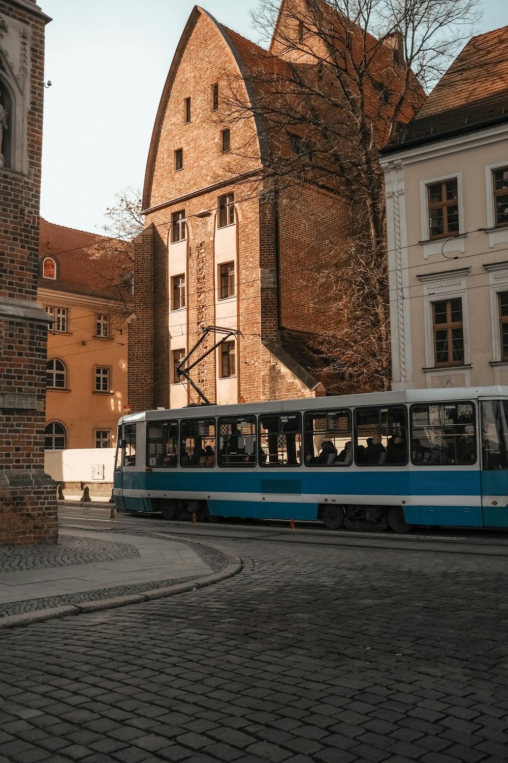 a blue and white train traveling past tall buildings