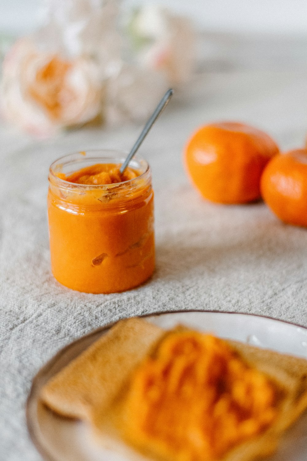 a small jar of orange marmalade next to some oranges