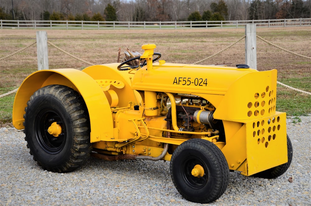 a yellow tractor parked on top of a gravel field