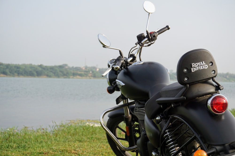 a black motorcycle parked next to a body of water