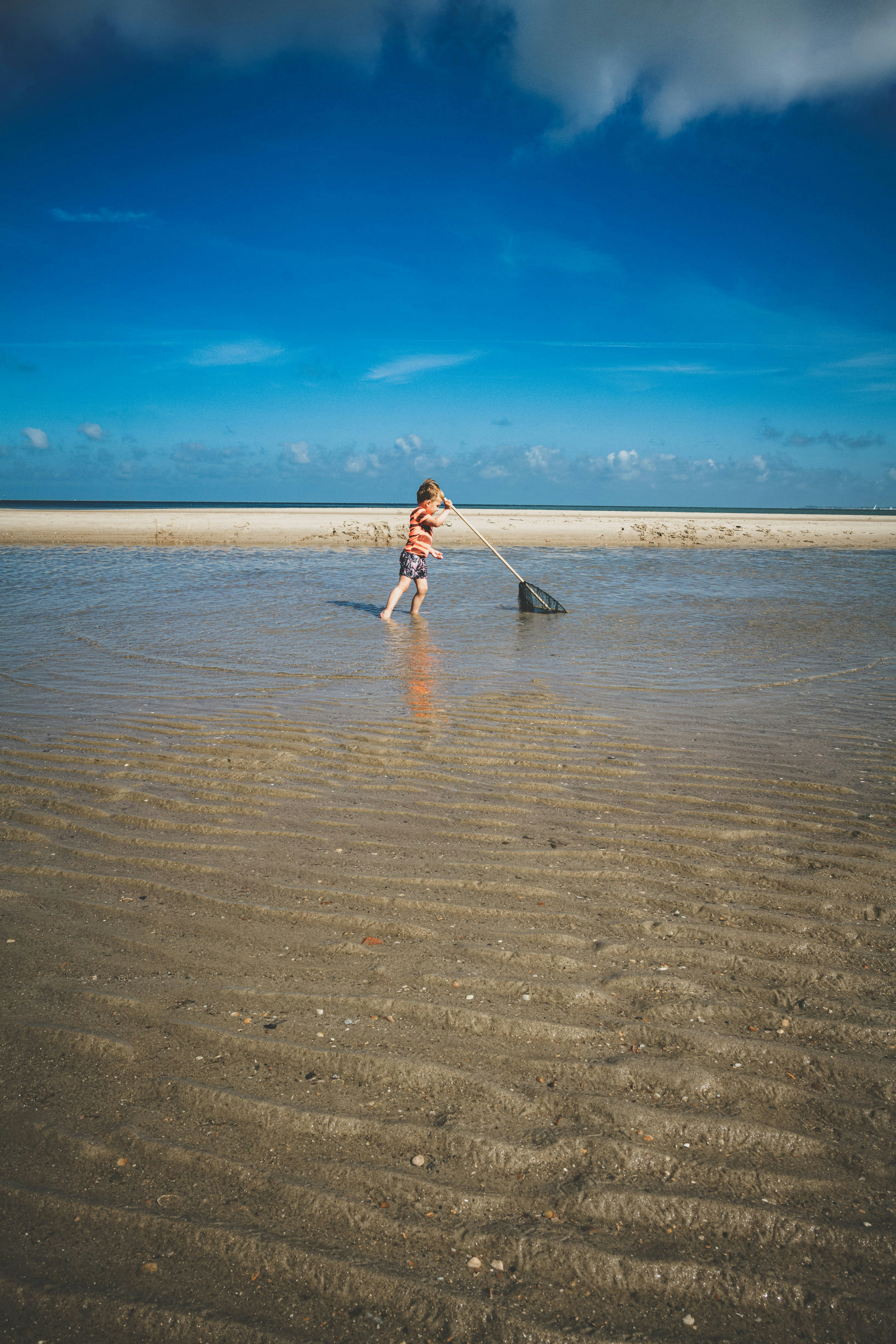 uma menina de pé em águas rasas em uma praia