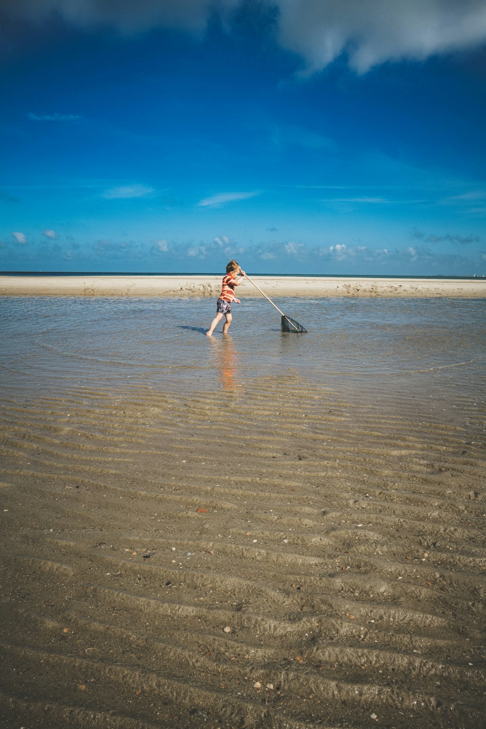 a little girl standing in shallow water on a beach
