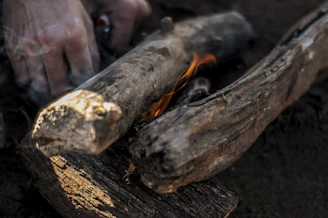A close-up of hands striking flint to spark a primitive fire with smoke rising.