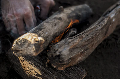 A close-up of hands striking flint to spark a primitive fire with smoke rising.