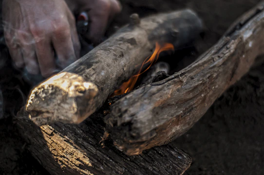 Hands demonstrating fire-starting with flint and steel in a forest setting.