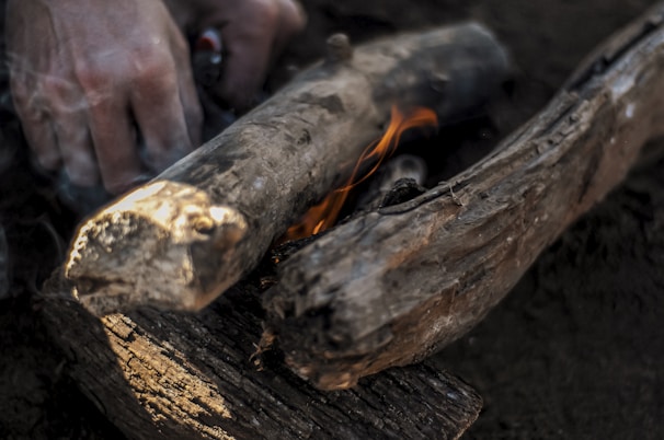 Close-up of hands starting a fire using traditional flint and steel tools surrounded by dry leaves.