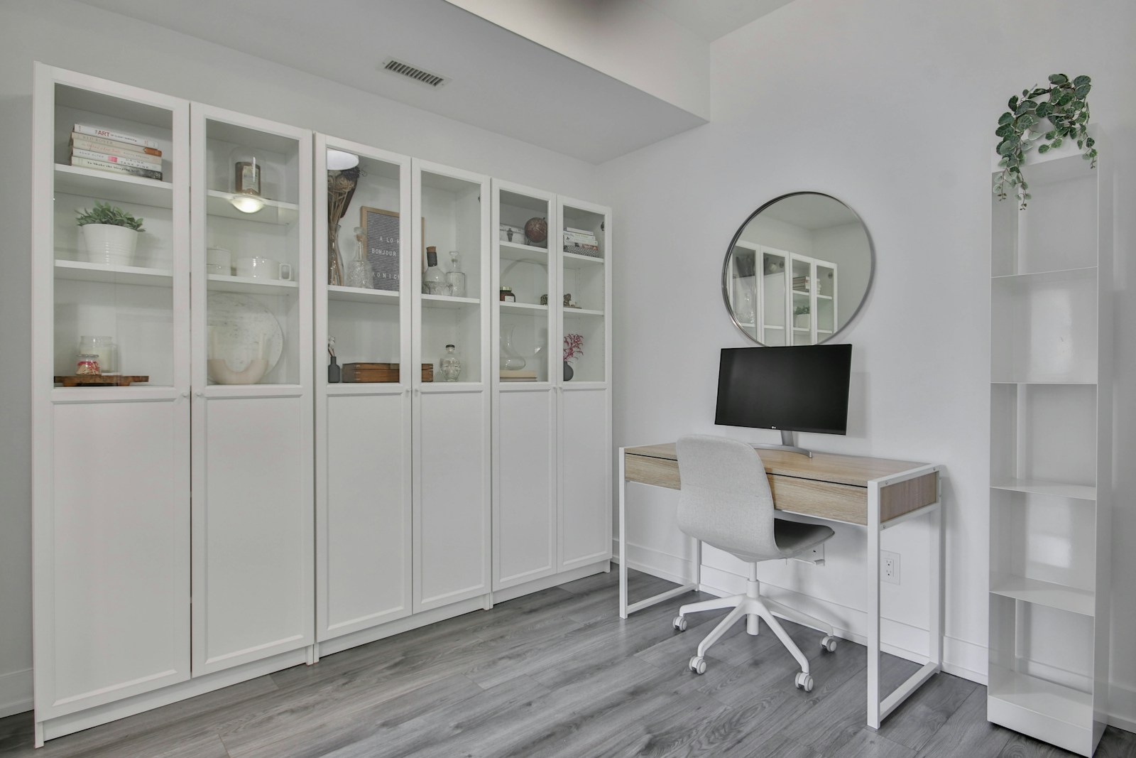 small white desk with monitor and chair next to glass cabinets in studio