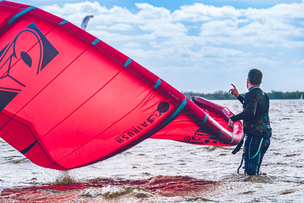 a man in a wet suit holding a red sail