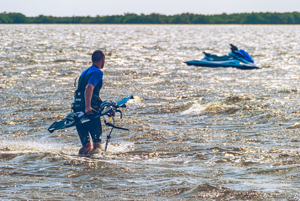 a man in a wet suit carrying a surfboard in the water