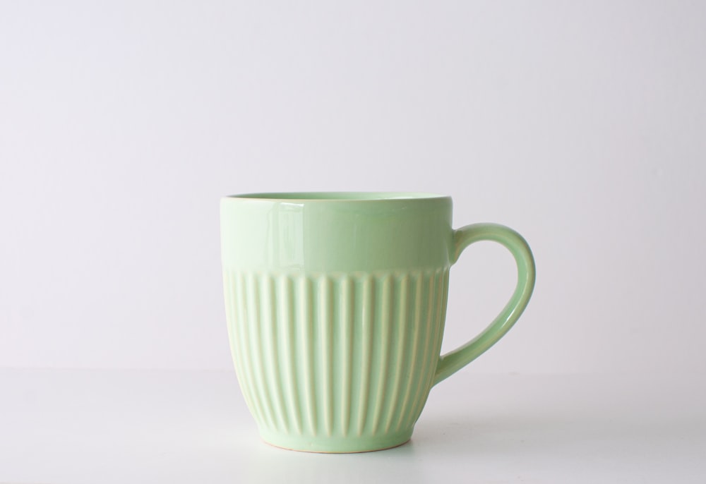a green coffee cup sitting on top of a table