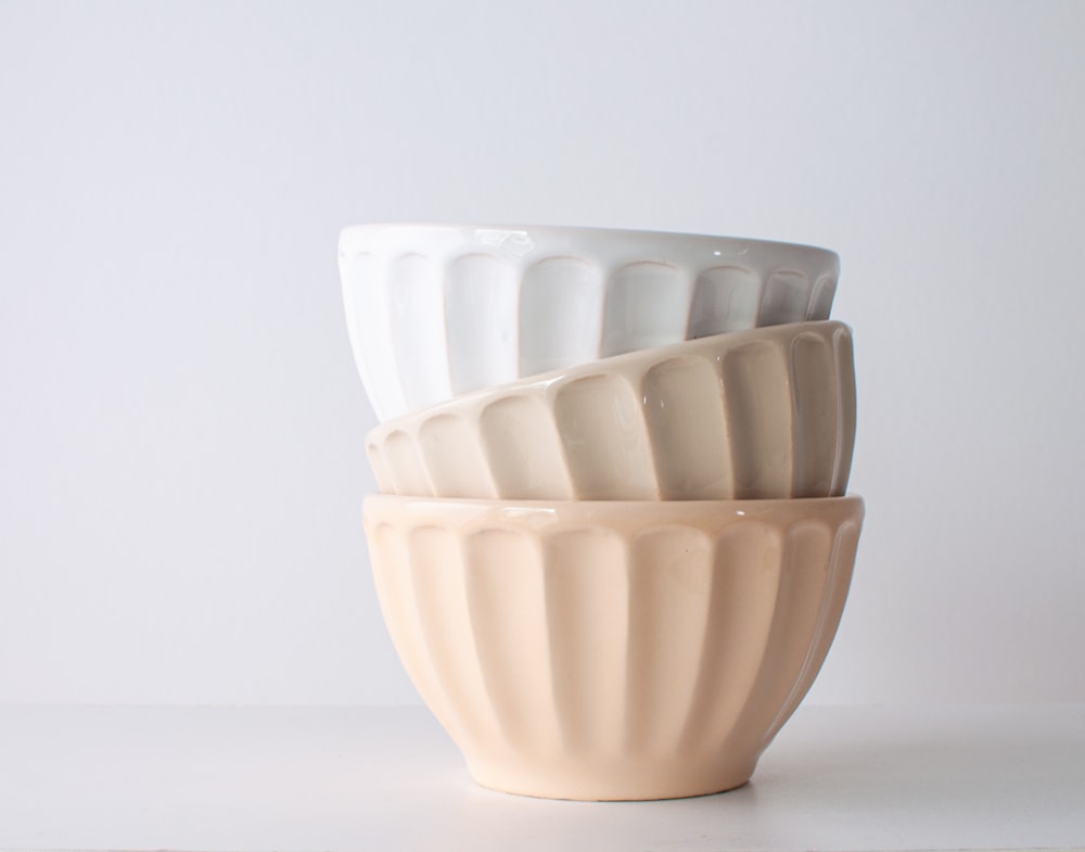 a stack of white and beige cups sitting on top of a table